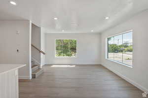Unfurnished living room featuring light wood-style flooring, healthy amount of natural light, recessed lighting, and stairs