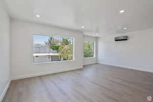 Unfurnished room featuring recessed lighting, light wood-style flooring, and a wall unit AC