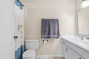 Bathroom with curtained shower, light tile patterned floors, and vanity