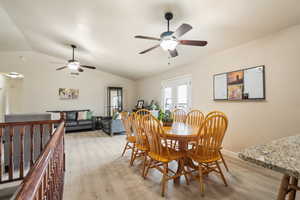 Dining room with light wood-style flooring, lofted ceiling, and a ceiling fan