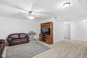 Living room featuring a textured ceiling, light wood-style floors, and ceiling fan
