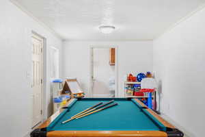Recreation room featuring a textured ceiling, ornamental molding, and billiards