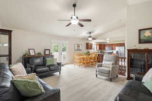 Living area featuring light wood finished floors, lofted ceiling, and ceiling fan