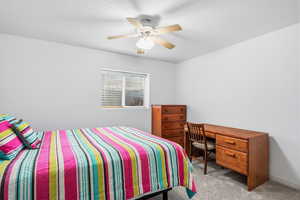 Carpeted bedroom featuring ceiling fan and a textured ceiling
