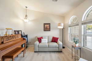 Sitting room with wood finished floors and vaulted ceiling