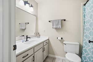 Full bath featuring curtained shower, light tile patterned flooring, and vanity
