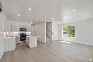 Kitchen featuring a center island, open floor plan, appliances with stainless steel finishes, light wood-style flooring, and recessed lighting