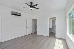 Unfurnished bedroom with light wood-type flooring, a walk in closet, recessed lighting, a ceiling fan, and a wall mounted AC