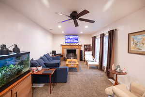 Living area with light colored carpet, a fireplace, recessed lighting, and a ceiling fan