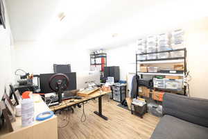 Home office with light wood-style flooring and vaulted ceiling