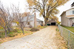 View of home's exterior with a detached garage, an outdoor structure, a chimney, and driveway