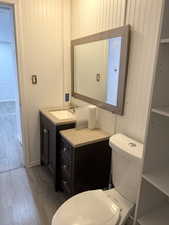 Half bath with light wood-type flooring, vanity, and wooden walls