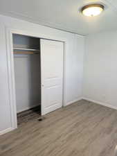 Unfurnished bedroom featuring light wood-style floors, a textured ceiling, and a closet