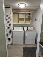 Laundry area with light wood-type flooring and washer and clothes dryer
