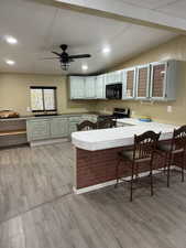 Kitchen featuring a kitchen breakfast bar, a peninsula, gas stove, light wood-style floors, and recessed lighting