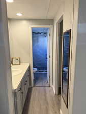Full bath with vanity, a shower stall, light wood-style floors, a textured ceiling, and recessed lighting