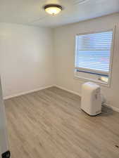 Spare room featuring light wood-type flooring and a textured ceiling