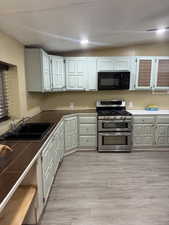 Kitchen with double oven range, light wood-style floors, and black microwave