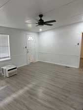 Foyer entrance featuring wood finished floors, a textured wall, a wall unit AC, ceiling fan, and a textured ceiling