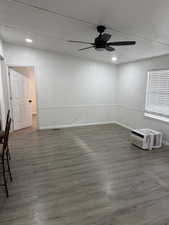 Unfurnished room with dark wood-style flooring, ceiling fan, and a wall mounted air conditioner