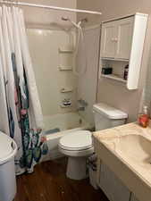 Bathroom with dark wood-style floors, shower / tub combo with curtain, and vanity