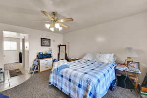 Bedroom featuring tile patterned floors, ceiling fan, and carpet