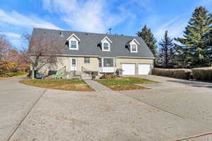 Cape cod-style house with driveway, a garage, brick siding, and roof with shingles