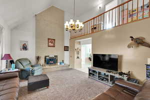Living area featuring light colored carpet, a brick fireplace, high vaulted ceiling, a chandelier, and light tile patterned floors