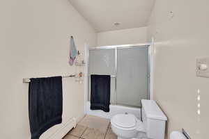 Full bathroom with tile patterned floors, bath / shower combo with glass door, and baseboard heating