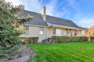 Rear view of property with a yard, a chimney, a shingled roof, and brick siding