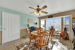 Dining area featuring light tile patterned flooring, a ceiling fan, and a textured ceiling