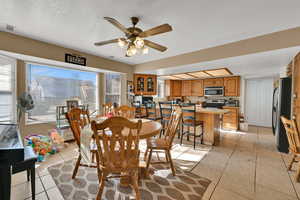 Dining room with light tile patterned floors, ceiling fan, and a textured ceiling