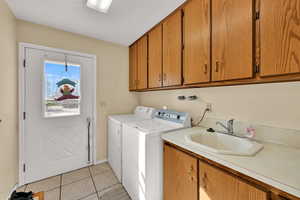 Laundry room featuring light tile patterned flooring, cabinet space, and washer and clothes dryer