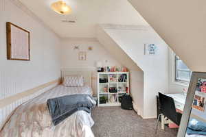 Carpeted bedroom featuring ornamental molding and wood walls