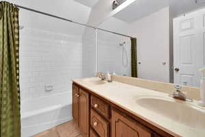 Full bath with light tile patterned floors, double vanity, and shower / tub combo with curtain