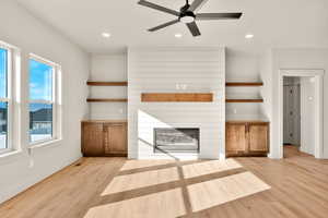 Unfurnished living room with a large fireplace, light wood-style floors, recessed lighting, and ceiling fan
