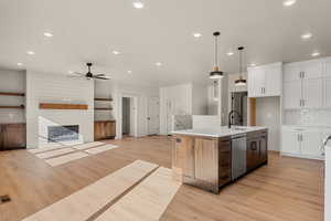 Kitchen featuring open floor plan, white cabinetry, light wood-type flooring, decorative light fixtures, and recessed lighting
