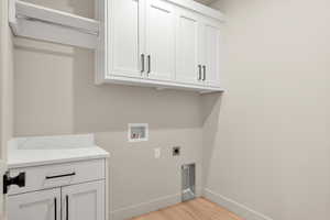 Laundry area featuring light wood finished floors, hookup for a washing machine, cabinet space, and hookup for an electric dryer