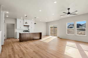 Kitchen with open floor plan, a kitchen island with sink, decorative backsplash, white cabinets, and recessed lighting