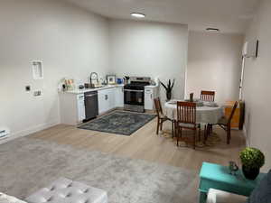 Kitchen with white cabinetry, stainless steel appliances, and light wood-style flooring