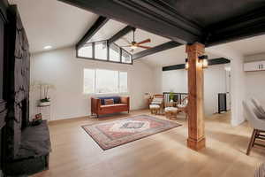 Living room featuring light wood-type flooring, a large fireplace, and ceiling fan