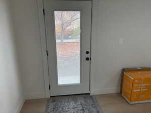 Doorway with baseboards and wood finished floors