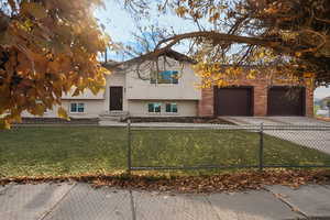 Split foyer home featuring brick siding, driveway, and a fenced front yard