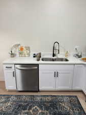 Bar featuring white cabinetry, light wood-type flooring, and dishwasher