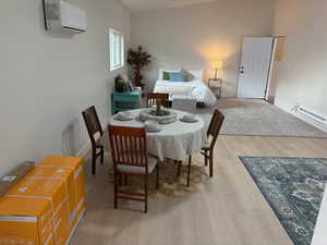 Dining room featuring an AC wall unit, light wood-style floors, and baseboard heating