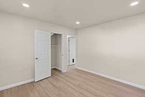 Unfurnished bedroom with a spacious closet, light wood finished floors, and recessed lighting