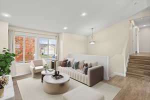 Living room with wood finished floors, recessed lighting, stairway, and lofted ceiling
