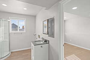Washroom with light wood-type flooring, recessed lighting, and electric panel