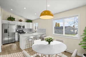 Kitchen featuring stainless steel appliances, tasteful backsplash, light wood-style floors, recessed lighting, and white cabinetry