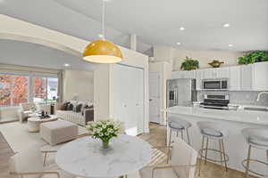Dining room with vaulted ceiling, recessed lighting, light wood-style floors, and arched walkways